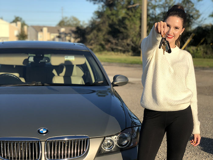 Woman holding car keys in front of BMW